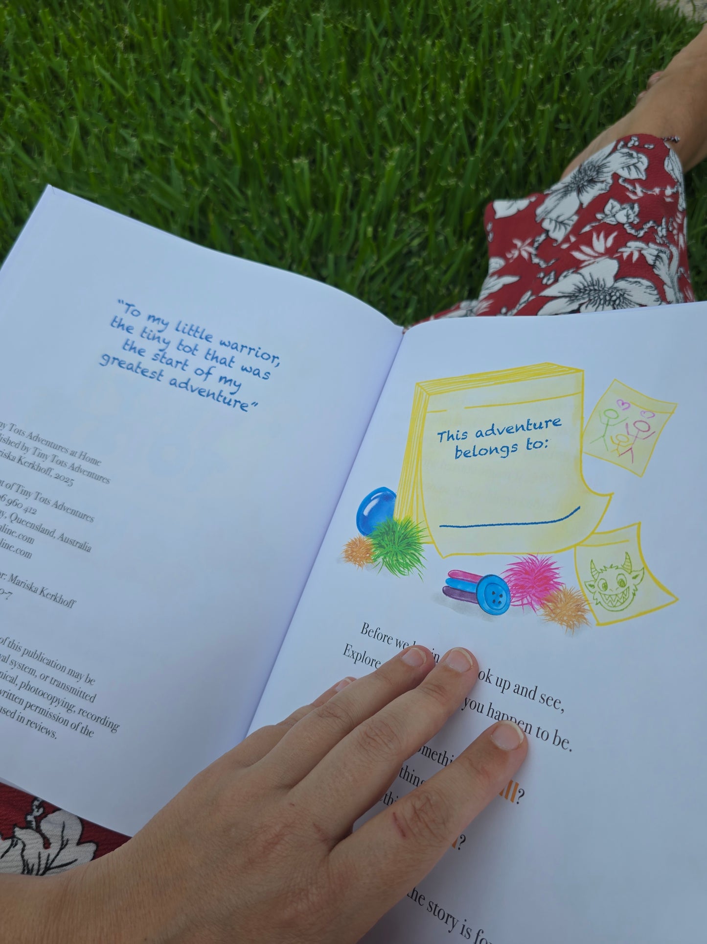 Person reading a book with colorful illustrations on grass