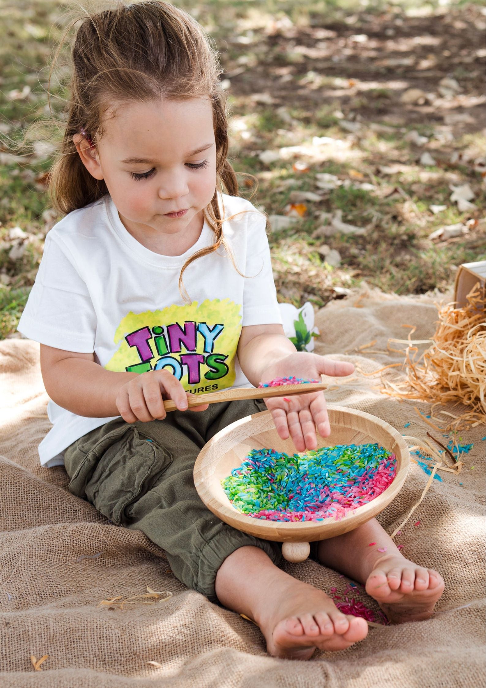 Child playing with colorful rice outdoors
