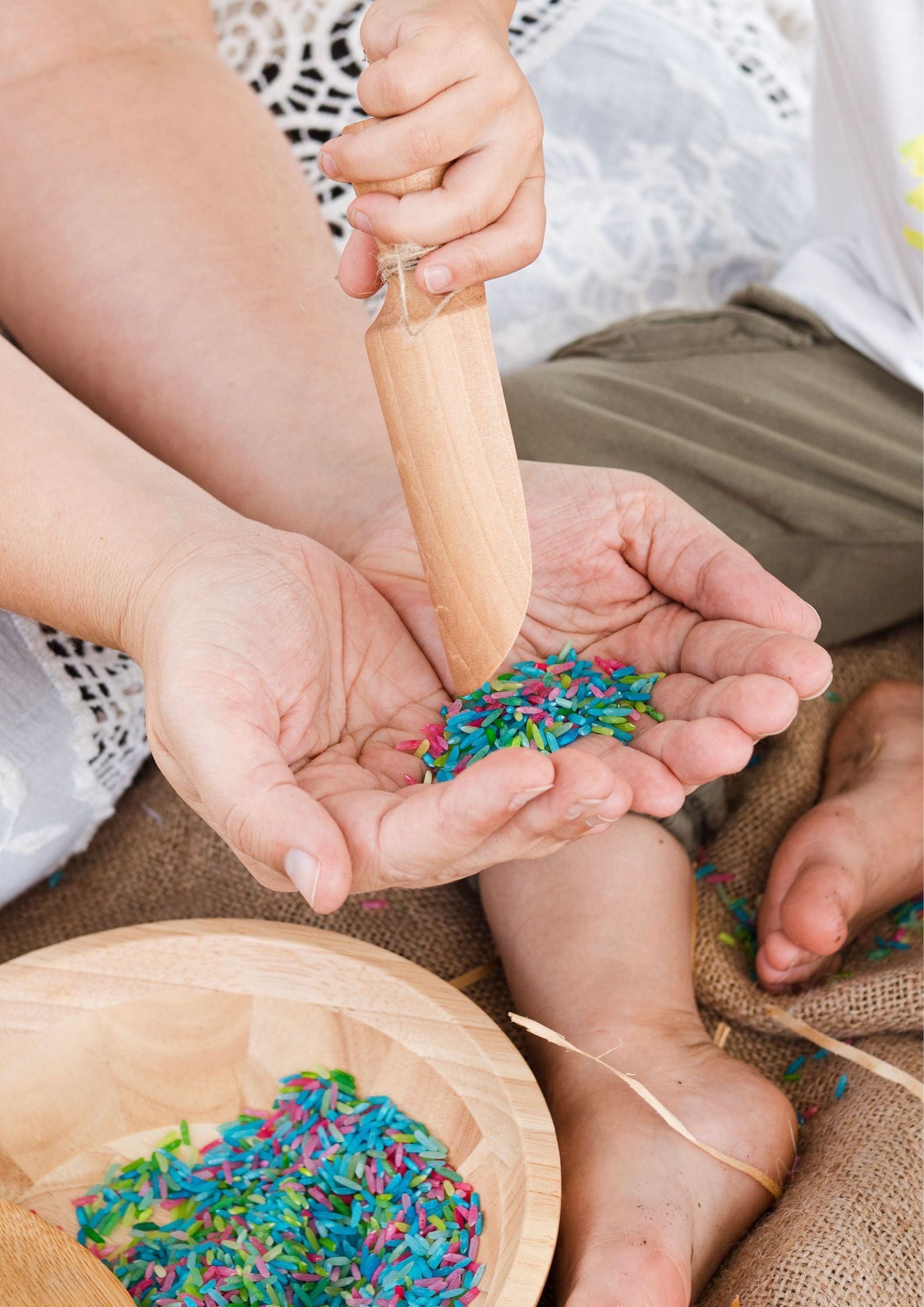 Children playing with colorful sprinkles on a wooden surface
