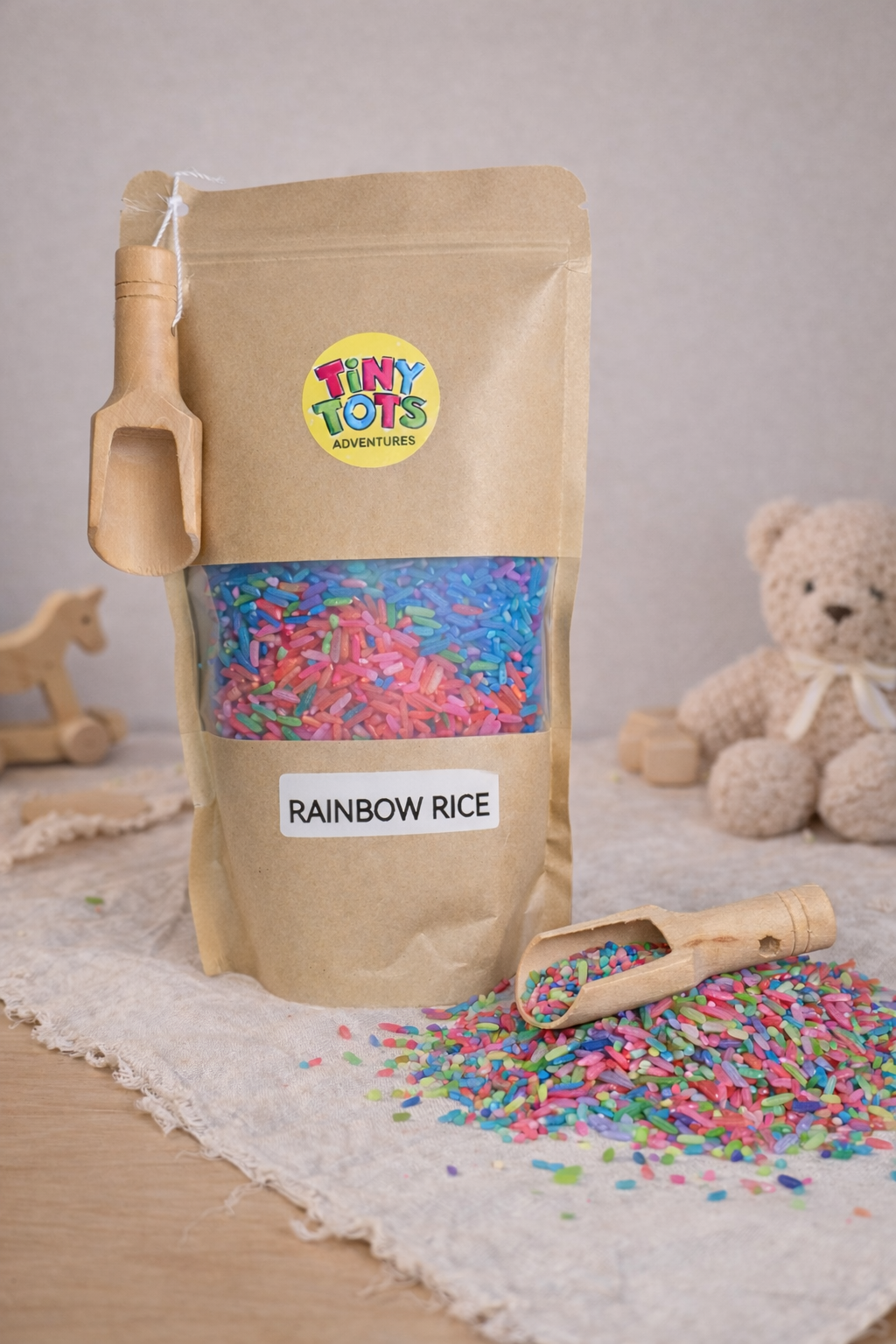 brown bag with tiny tots logo containing coloured rice and a small wooden spoon